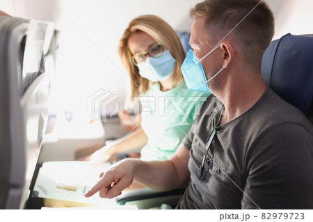 Young married couple flying in airplane wearing protective medical masks 82979723