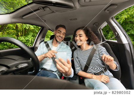 Middle-eastern guy driver travelling with girlfriend, setting gps on cellphone Middle-eastern guy driver travelling with girlfriend, setting gps on cellphone 82980302