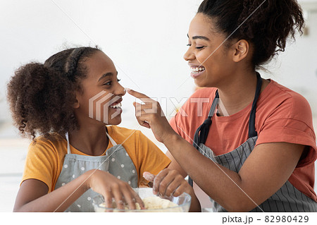 Closeup of black woman staining her daughter nose with flour 82980429