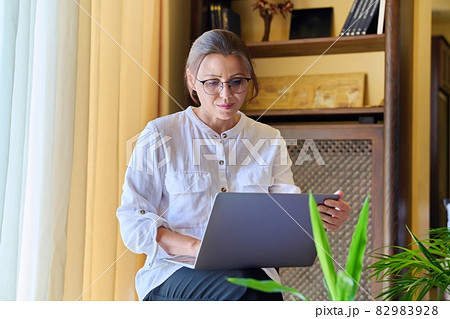 Middle-aged woman psychologist in an office with a laptop. 82983928