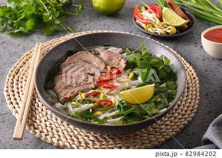 Pho Bo Soup with beef in gray bowl on gray. Vietnamese cuisine. Pho Bo Soup with beef in gray bowl on gray. Vietnamese cuisine. 82984202