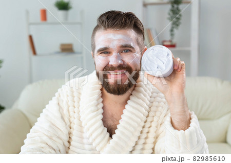 Bearded guy applying anti-wrinkle cream on his face. Skin care and spa for man concept. 82985610