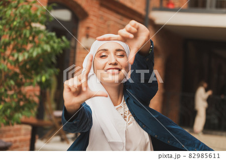 Portrait of young muslim girl making a camera frame with fingers outdoors. 82985611