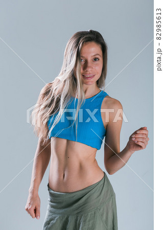 Fitness girl with sporty body posing at studio on grey background. Fitness smiling model in sportswear. Weight Loss. Healthy lifestyle. Sporty healthy female. 82985613