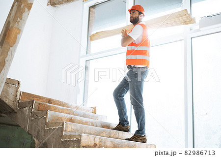 Builder man in hardhat carrying timber on building site, close up . 82986713