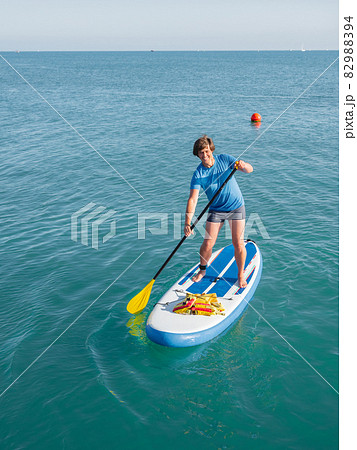 Handsome paddle boarder. Sportsman paddling on stand up paddleboard. SUP surfing. Active lifestyle. Outdoor recreation. Vacation on seaside. Handsome paddle boarder. Sportsman paddling on stand up paddleboard. SUP surfing. Active lifestyle. Outdoor recreation. Vacation on seaside. 82988394