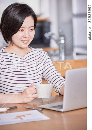 テレワーク中に気分転換にコーヒーを飲む若い女性 82988996