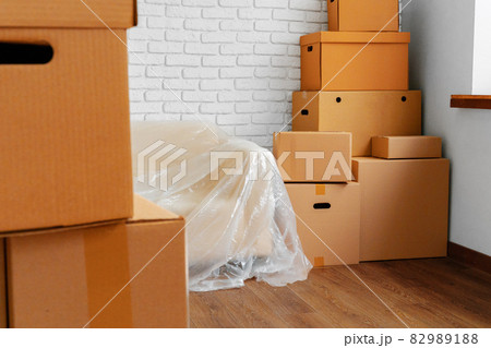 Packed sofa and stack of cardboard boxes in a room. Moving concept Packed sofa and stack of cardboard boxes in a room. Moving concept 82989188