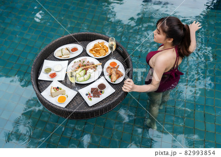 cheerful woman enjoying with floating food in swimming pool cheerful woman enjoying with floating food in swimming pool 82993854