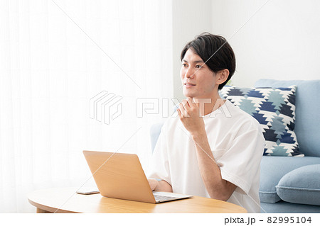 家でパソコンを使い仕事をする若い男性（ビジネスイメージ） 82995104