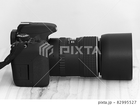 Modern entry-level DSLR camera and the prime lens with the lens hood side view. Modern entry-level DSLR camera and the prime lens with the lens hood side view. 82995527