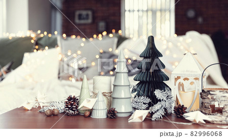 Christmas or New Year composition with various home decorations, different symbolic toys composed and ordered at coffee table with blurred Christmas lights background at sofa white cover. Family time 82996068