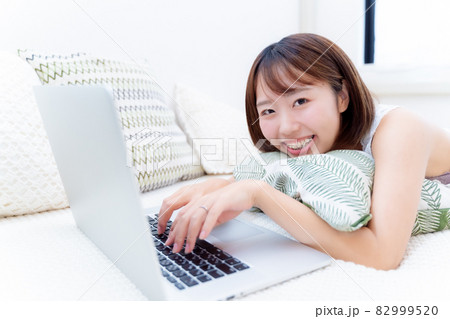 こちらに笑顔を見せるPC使用中の女性 82999520