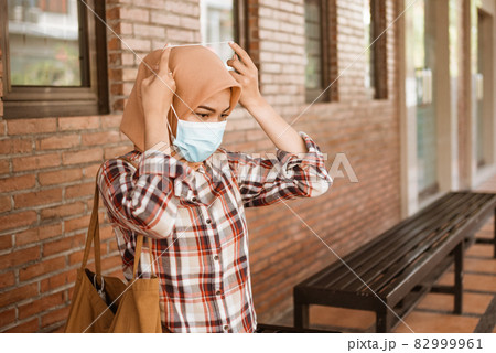 Coronavirus. Asian woman putting on a medical disposable mask to avoid viruses. Coronavirus. Asian woman putting on a medical disposable mask to avoid viruses. 82999961