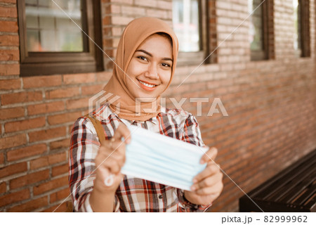 Coronavirus. Asian woman putting on a medical disposable mask to avoid viruses. 82999962