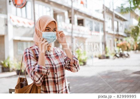 Coronavirus. Asian woman putting on a medical disposable mask to avoid viruses. 82999995