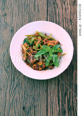 Stir spices with tropics eel in white dish on wooden floor. 83000238