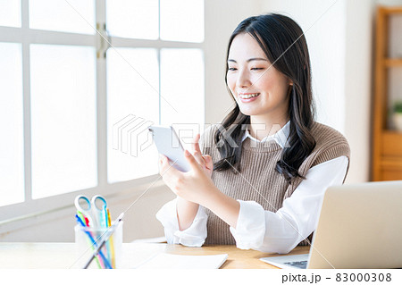 リビングでスマホを操作する女性 リビングでスマホを操作する女性 83000308