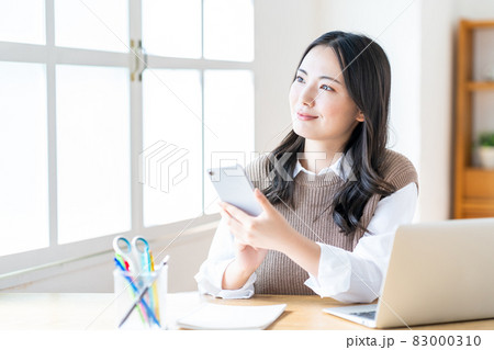 リビングでスマホを操作する女性 リビングでスマホを操作する女性 83000310