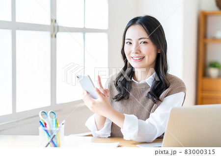 リビングでスマホを操作する女性 リビングでスマホを操作する女性 83000315