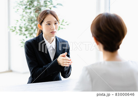 向かい合わせの人物と会話をする若い女性 向かい合わせの人物と会話をする若い女性 83000646