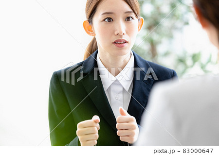 向かい合わせの人物と会話をする若い女性 83000647