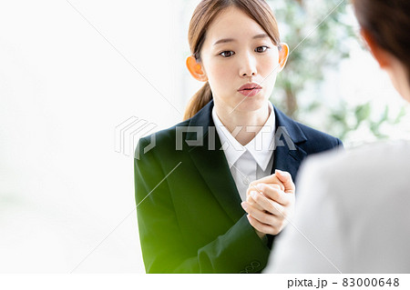 向かい合わせの人物と会話をする若い女性 83000648