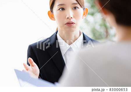 向かい合わせの人物と会話をする若い女性 83000653