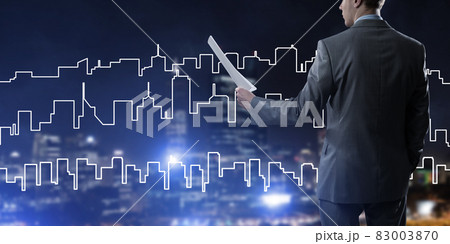 Man architect or engineer presenting construction concept and holding documents in hand Man architect or engineer presenting construction concept and holding documents in hand 83003870