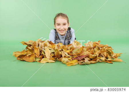 Autumn. Young girl holds autumn yellow leaves. Cute girl in school uniform. 83003974