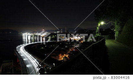 日本製鉄の瀬戸内製鉄所呉地区の工場夜景＝画面奥、操業中＝と道路を通行する車両の光跡 83004416