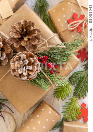 Wrapped Christmas present decorated with pine cones and juniper branches 83005943