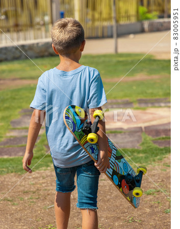 Preschooler boy keep a skateboard in hands in park Preschooler boy keep a skateboard in hands in park 83005951