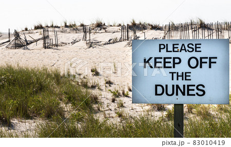 Keep off the dunes sign in front of sand dunes with broken fences on Fire Island Keep off the dunes sign in front of sand dunes with broken fences on Fire Island 83010419