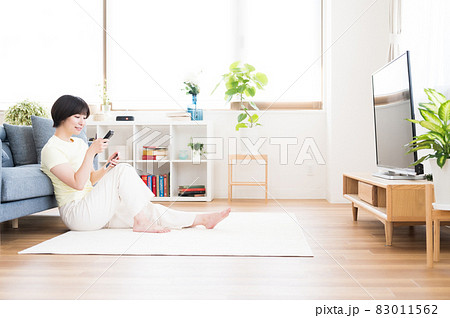 テレビを見ながらリモコンを操作する女性 83011562
