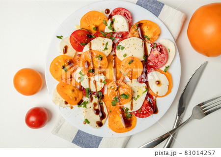 Fresh classic italian caprese salad with sliced red yellow tomatoes, mozzarella, olive oil, pepper and salt on light background. Healthy vegetarian diet food 83014257