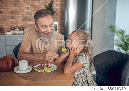 Family having breakfast together and dad trying to feed his daghter Family having breakfast together and dad trying to feed his daghter 83016339