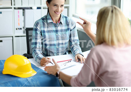 Woman designer architect makes project of house with client in office Woman designer architect makes project of house with client in office 83016774