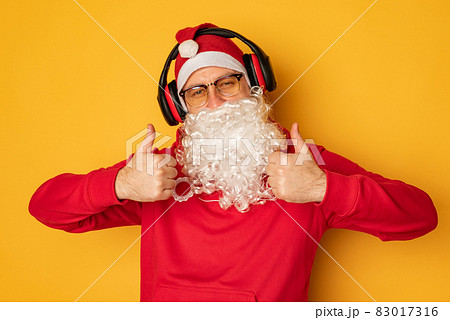 DJ Santa Claus in headphones. Christmas songs and music. yellow background. DJ Santa Claus in headphones. Christmas songs and music. yellow background. 83017316