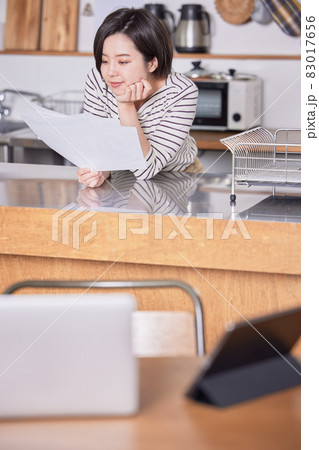 テレワークで席を立ち資料を見る若い女性 83017656