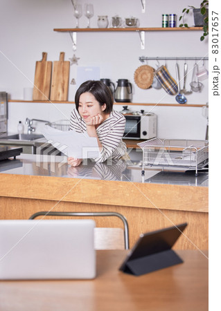 テレワークで席を立ち資料を見る若い女性 83017657