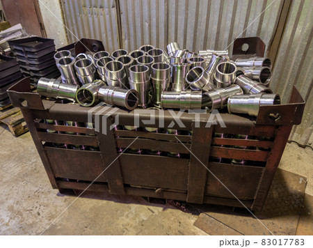 shiny steel parts overflowing big intermodal steel container box on factory floor 83017783