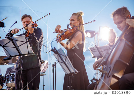 Musical ensemble playing classic instrumental music against blue sky 83018390