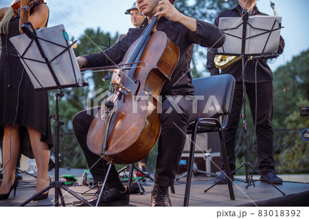 Male musician playing violoncello in orchestra on the street 83018392