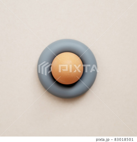 A beige egg stands in a gray rubber expander on a light background. Top view 83018501