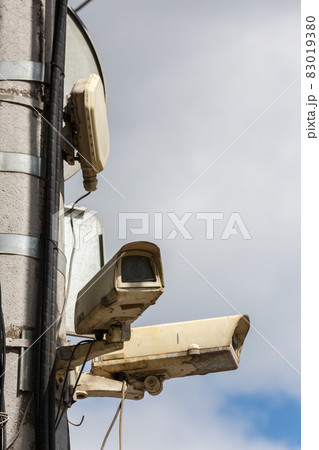 two old cctv security surveillance cameras on street light pole on blue sky background 83019380