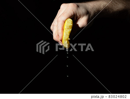lemon squeezed in hand of man on black background 83024802
