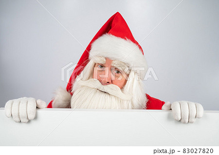 Santa Claus peeks out from behind an ad on a white background. Merry Christmas. Santa Claus peeks out from behind an ad on a white background. Merry Christmas. 83027820