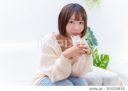 スマホを持って笑顔でこちらを見つめる女性 83028830