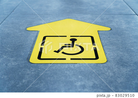 A drawing of a wheelchair on a yellow arrow glued to the tile in the waiting room 83029510